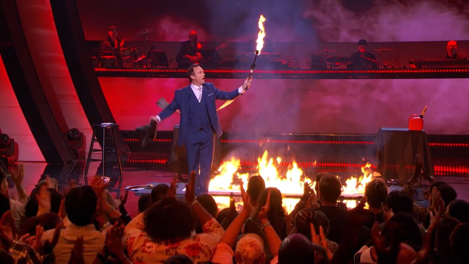 Man on stage holding a pole on fire