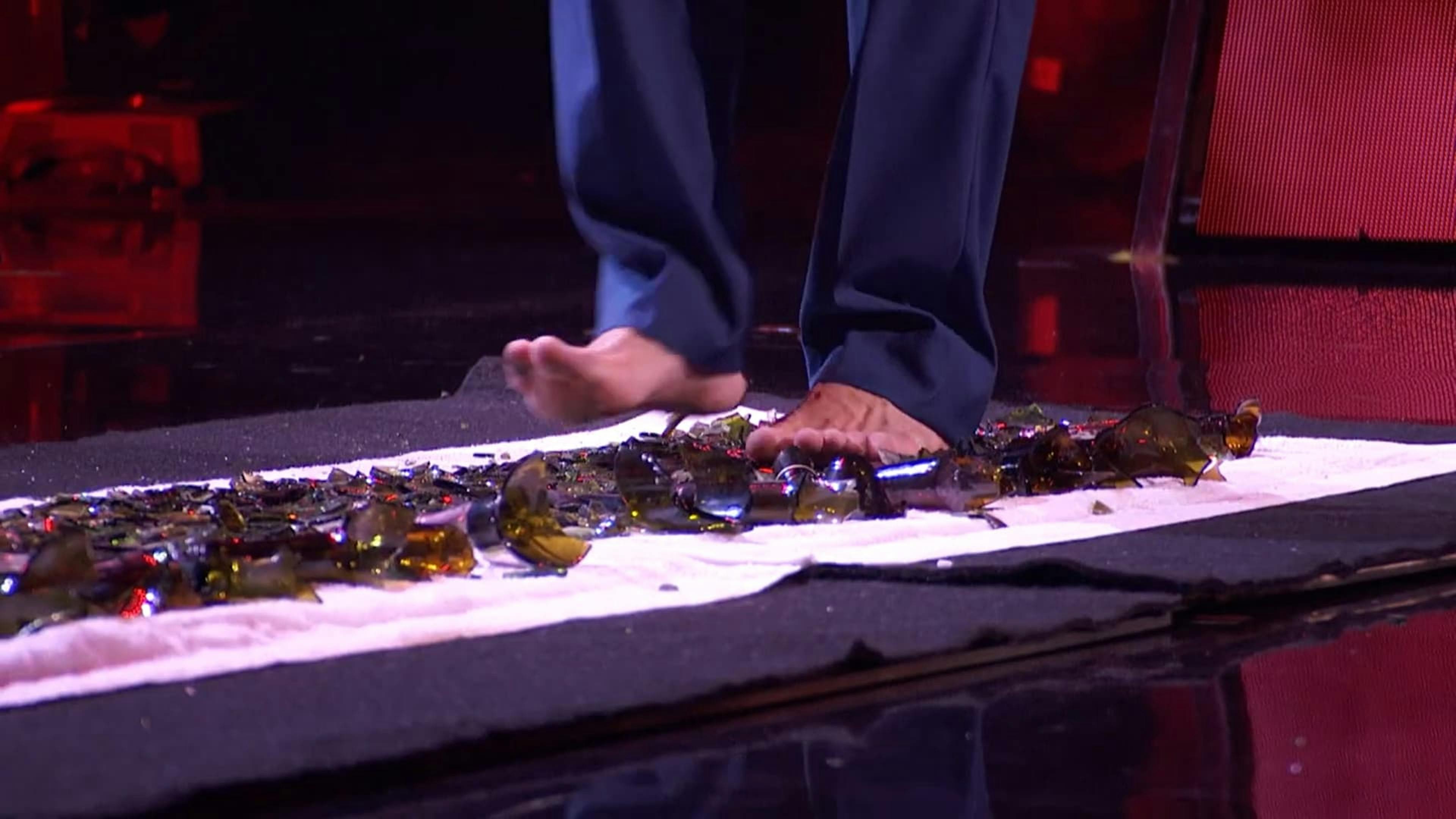 Man barefoot walking on broken glass