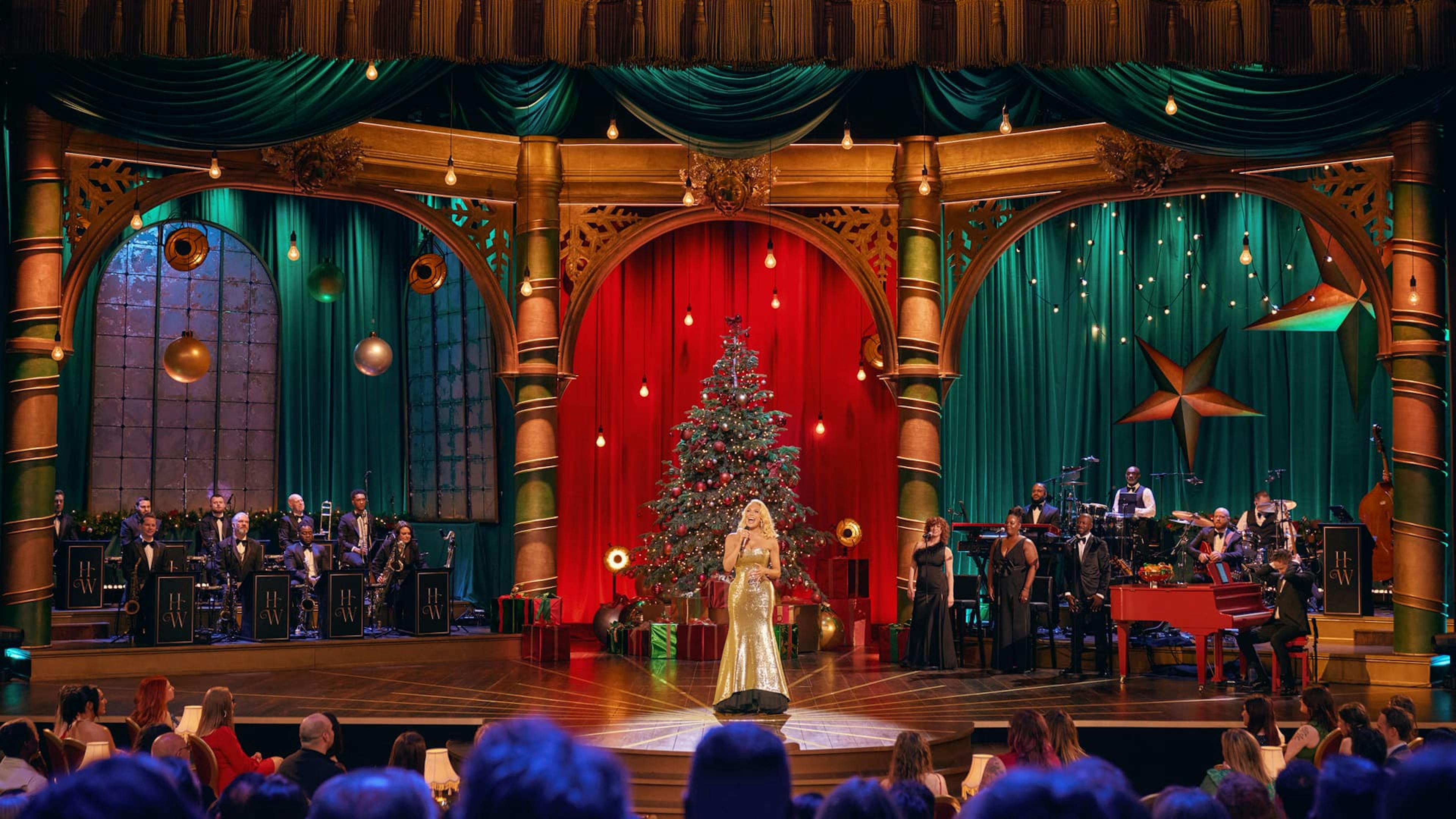 Woman and band performing on stage in front of Christmas Tree
