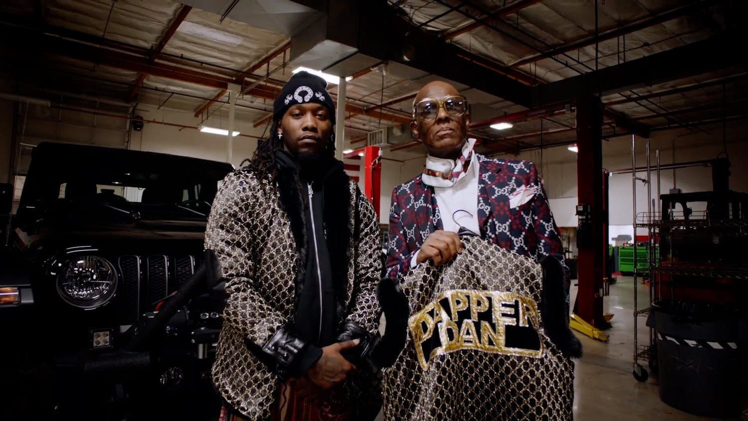 Two men looking at camera holding jacket with gold on it