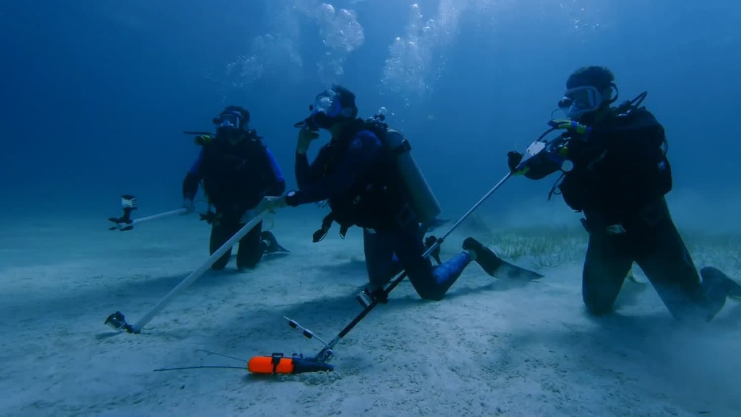 Three divers at bottom of sea