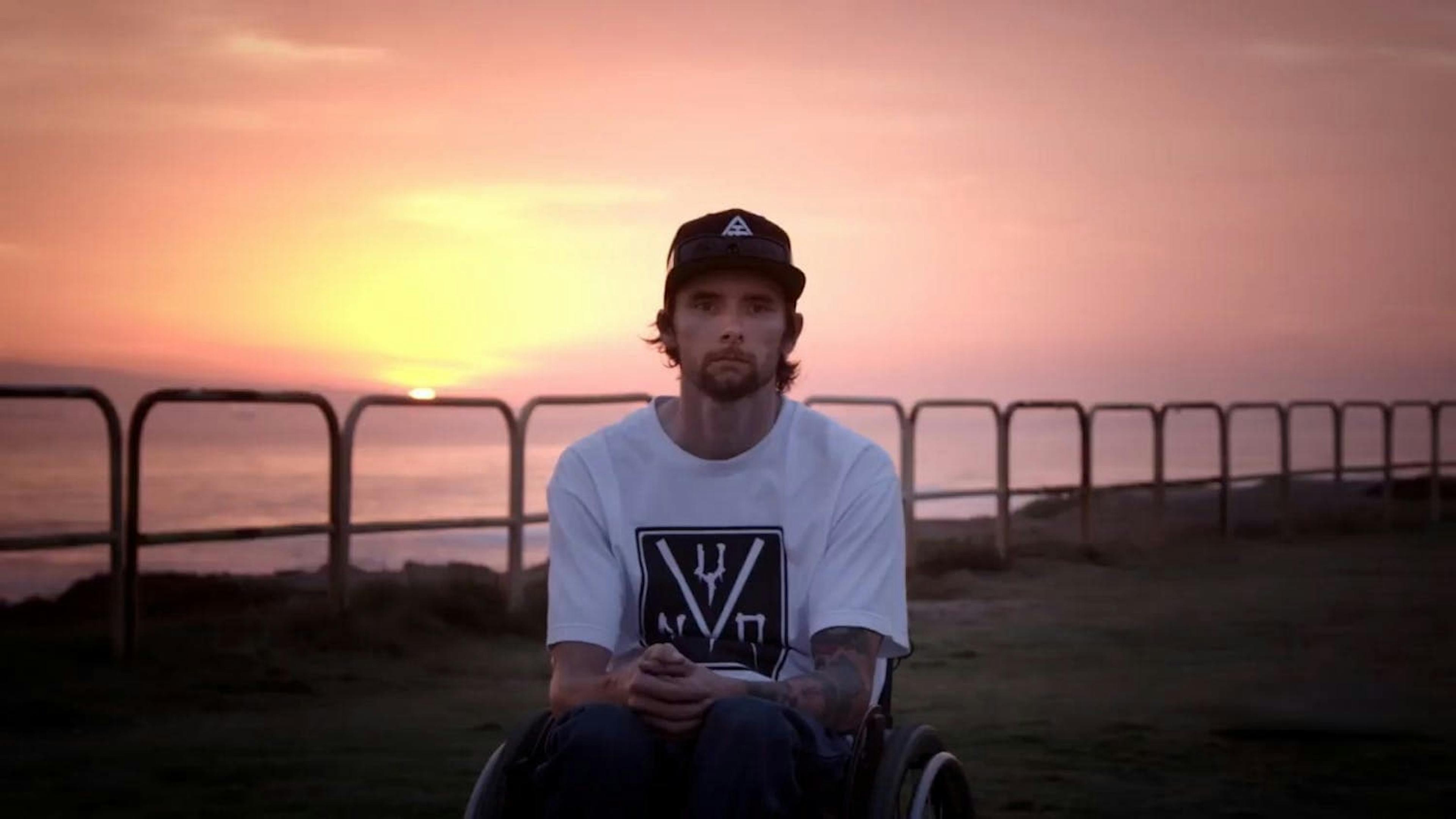 Man sat in front of sunset looking at camera