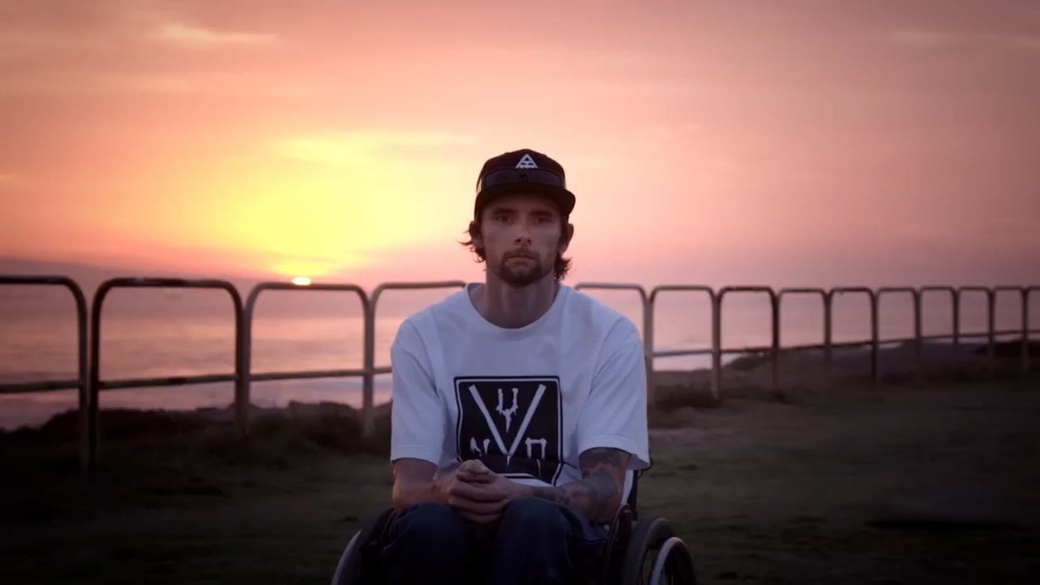 Man sat in front of sunset looking at camera