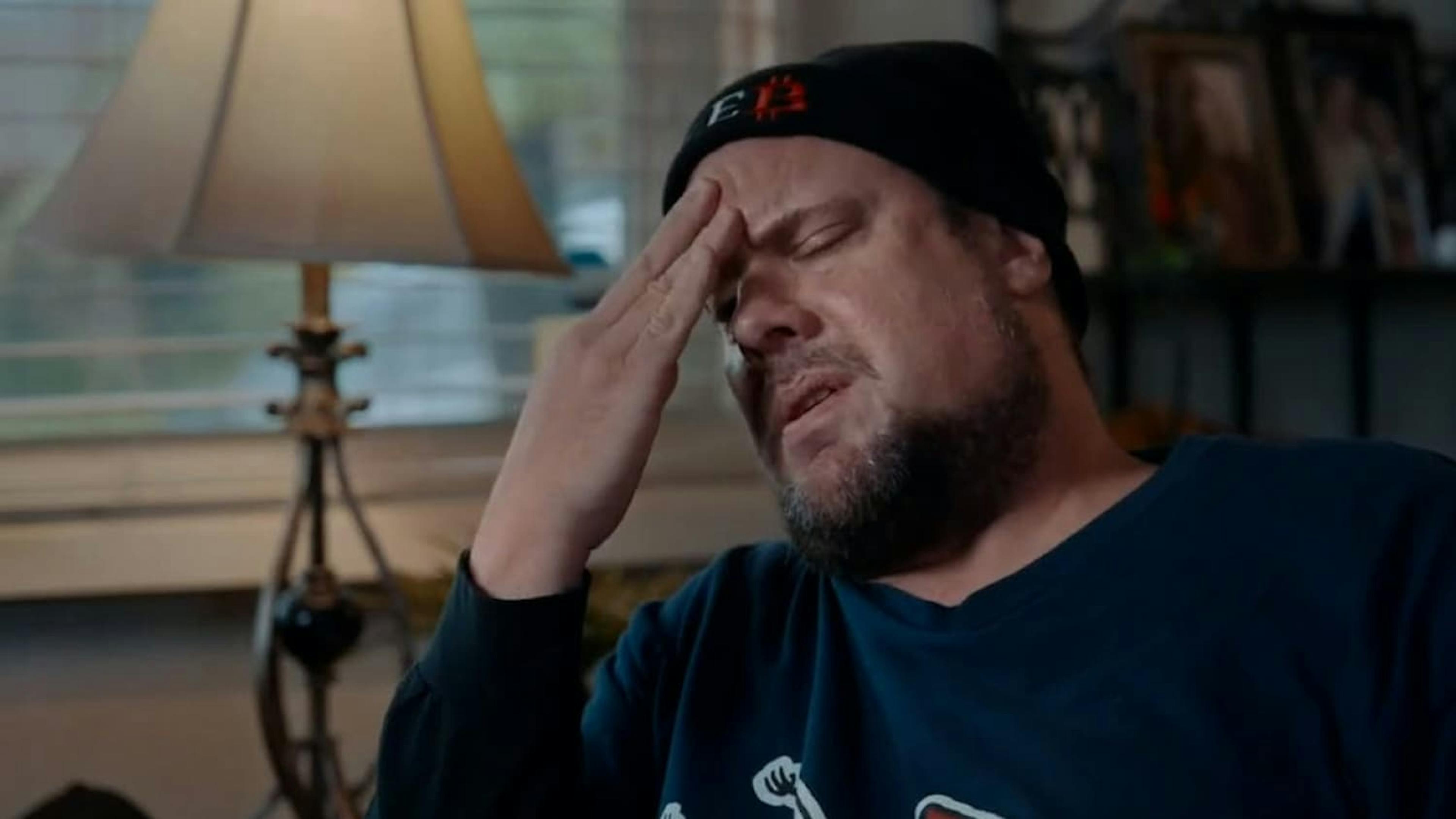 Man being interviewed with head in his hands