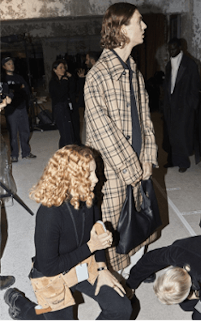 A backstage photo of an Ami Paris Fashion Show. The coloured image is showing two models waiting for the event to happen.