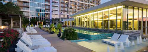 Dusk view of infinity-edge swimming pool and lounges and sky lounge exterior at AMLI Design District apartment building