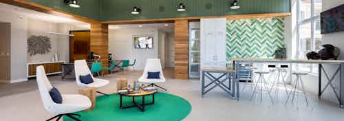 Interior of leasing office at AMLI Frisco Crossing apartment building with seating area, desks with chairs and big screen TV