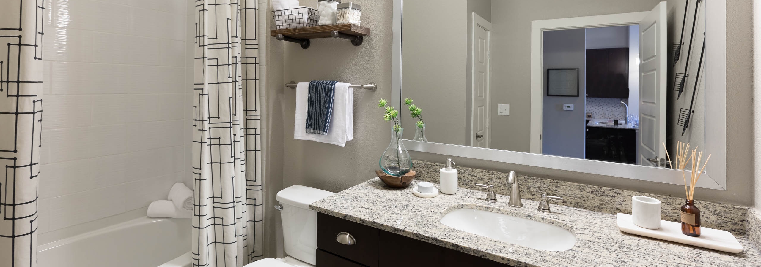 AMLI Frisco Crossing bathroom with and espresso cabinetry with granite countertop and framed mirror above and oval garden tub