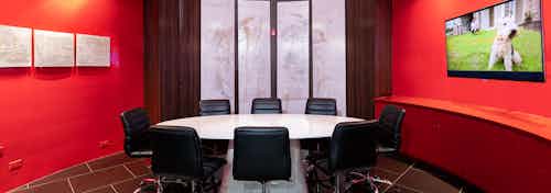 AMLI Uptown conference room with round white table table with eight black leather chairs and red walls and large window