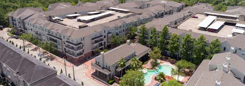 Daytime aerial view of AMLI Memorial Heights apartment buildings with view of curved pool and clubhouse in right foreground