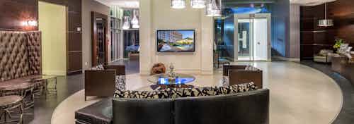 AMLI Design District apartments lobby with dark brown leather furniture and big screen TV with circular layered ceiling above