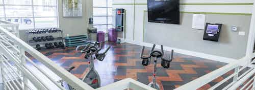 Interior view of a fitness on demand room at AMLI Arista apartments with stationary bicycles and free weights and television