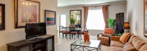 Interior of apartment living room at AMLI Memorial Heights with sectional couch, TV and dining room with large window