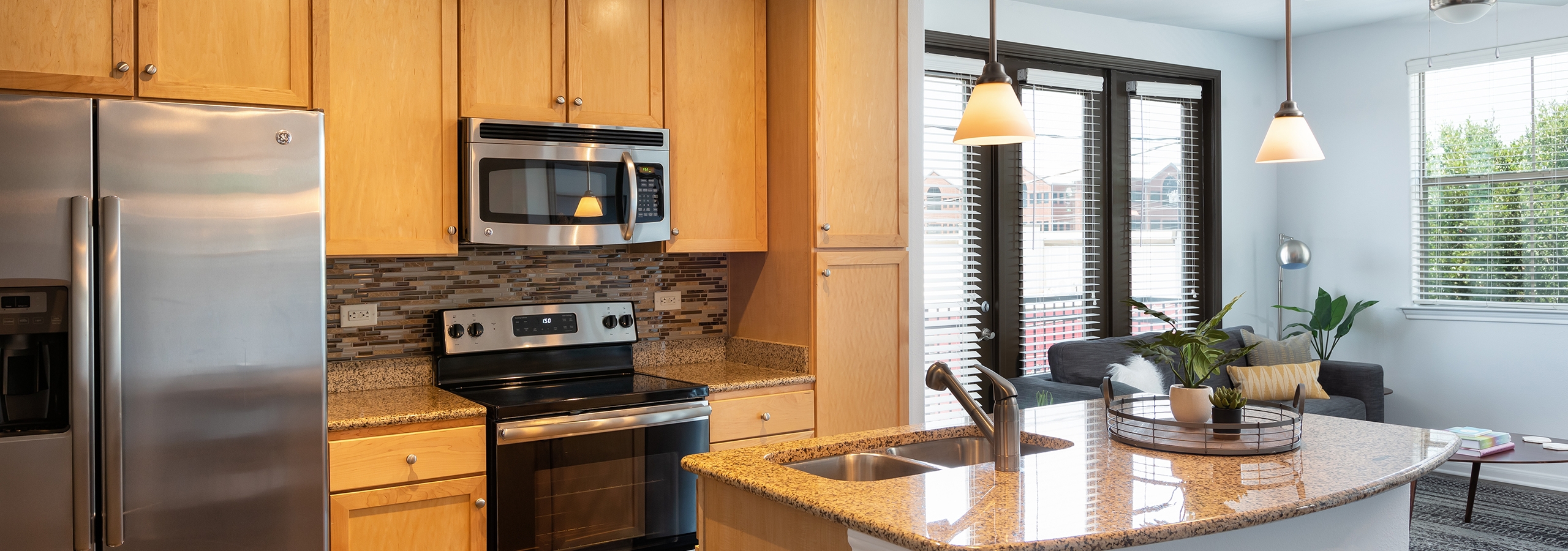 Daytime AMLI 300 apartment kitchen with an island, under mount deep stainless sink, and elegant granite counter tops