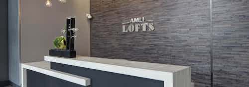 Interior view of the Clark lobby at AMLI Lofts which has a vibrant textured accent wall behind a modern black and white desk