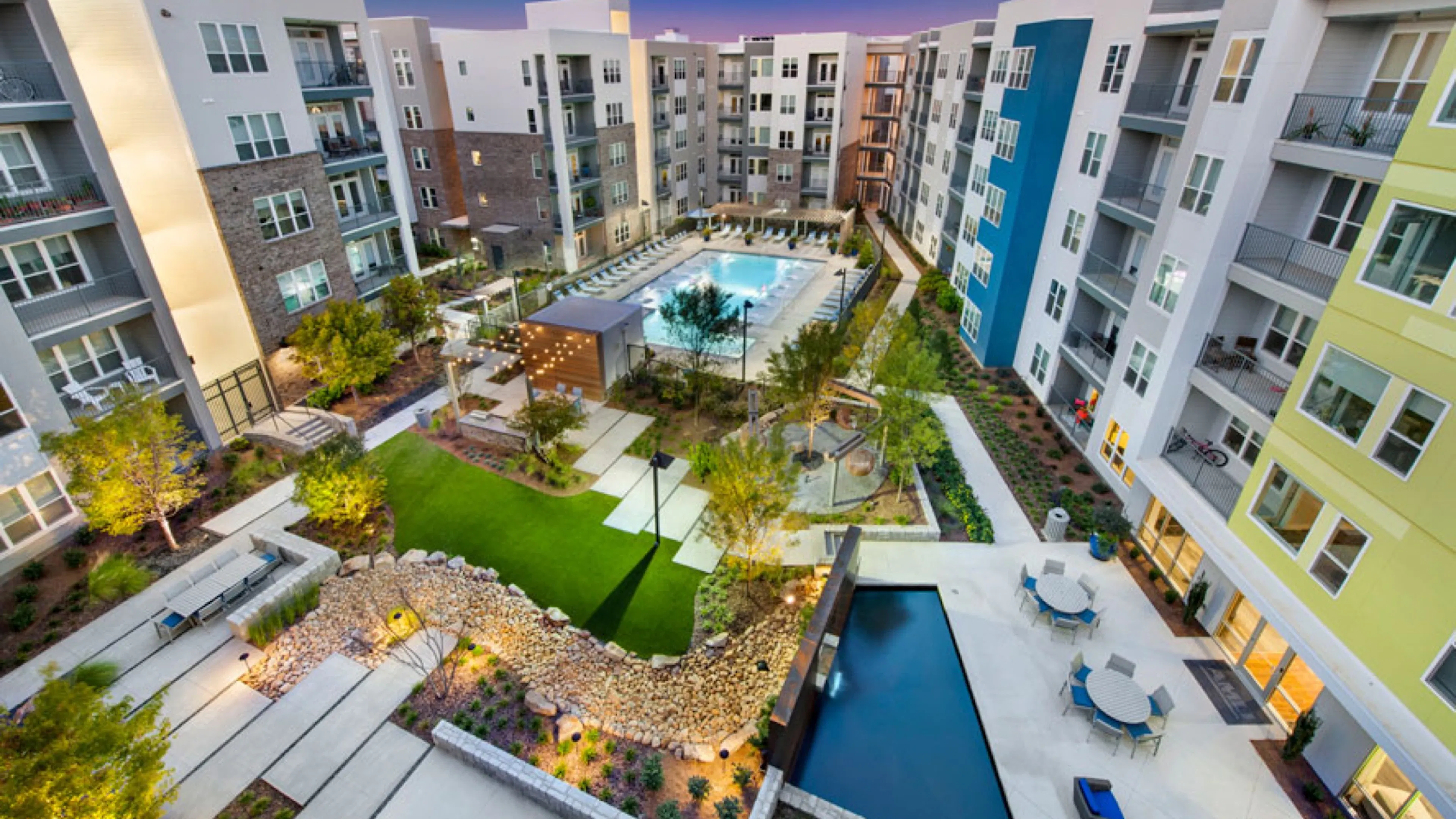 A wide angle view of a plant filled courtyard of a midrise apartment complex