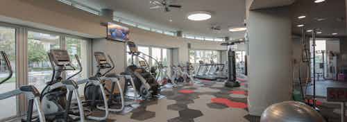 Interior of fitness center at AMLI Design District apartments with cardio machines and spin bikes and TV and ceiling fan above