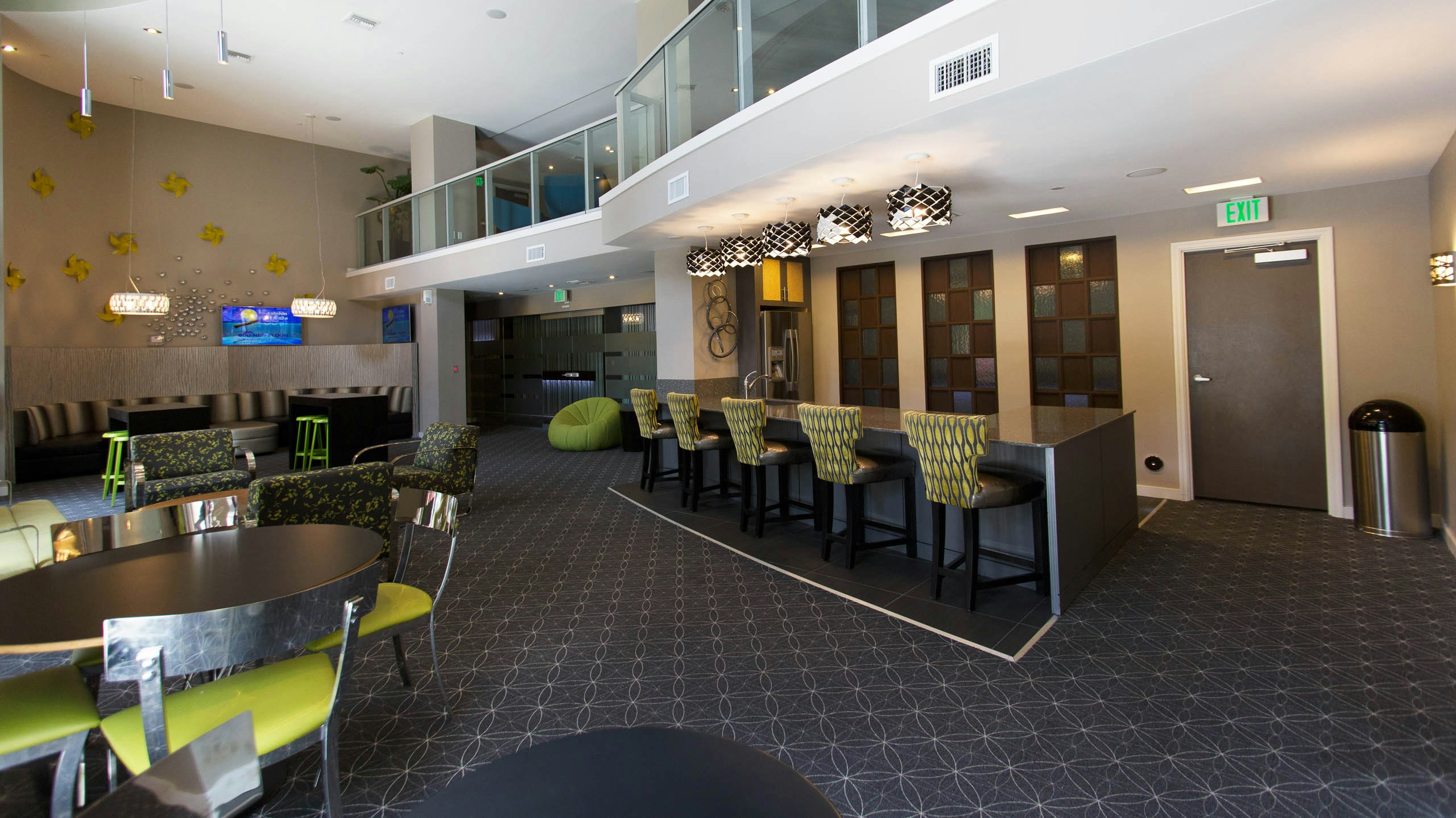 Two story resident lounge and AMLI Dadeland apartments with various seating areas with green chairs