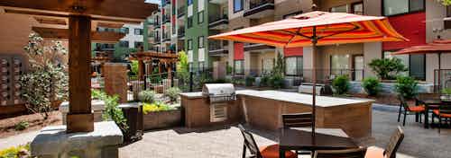AMLI Ponce Park outdoor grilling area with stainless steel grill and counter space for food prep and a table with an umbrella