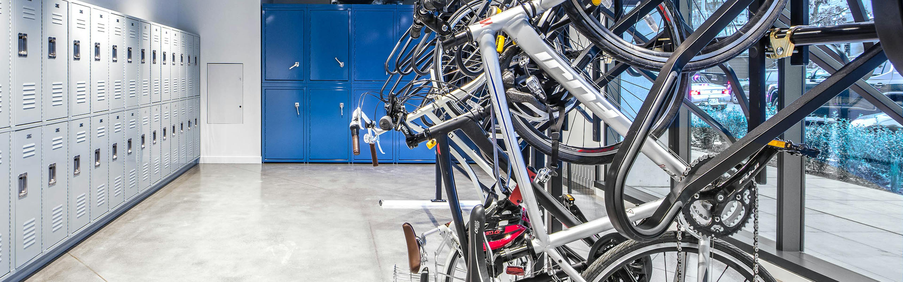 Interior bike room of AMLI Arc with bike storage tools and grey and bright blue storage lockers with large floor to ceiling windows facing the sidewalk  
