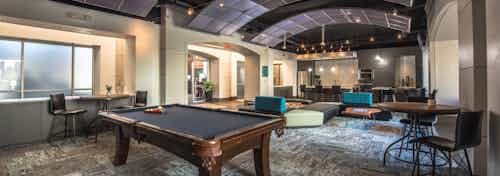 IAMLI Las Colinas resident lounge with billiards table and comfortable seating with tall ceiling and kitchen at back