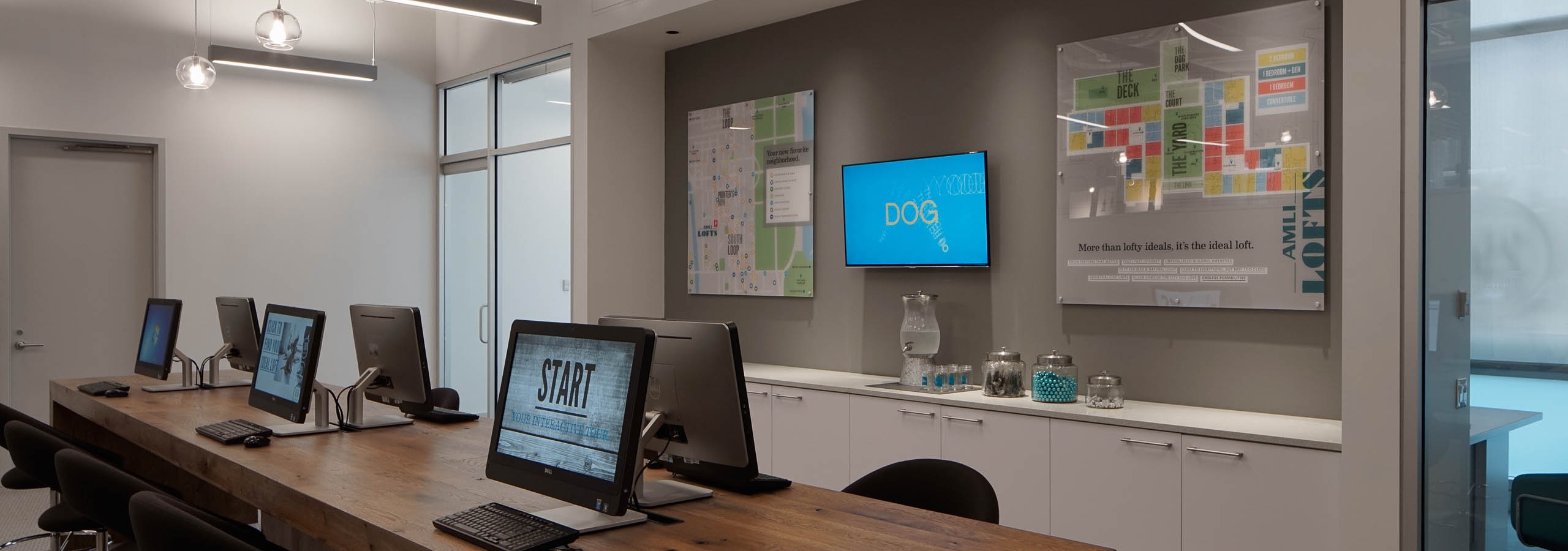 The leasing office at AMLI Lofts which has a long wooden desk with multiple computers and chairs set up to serve residents