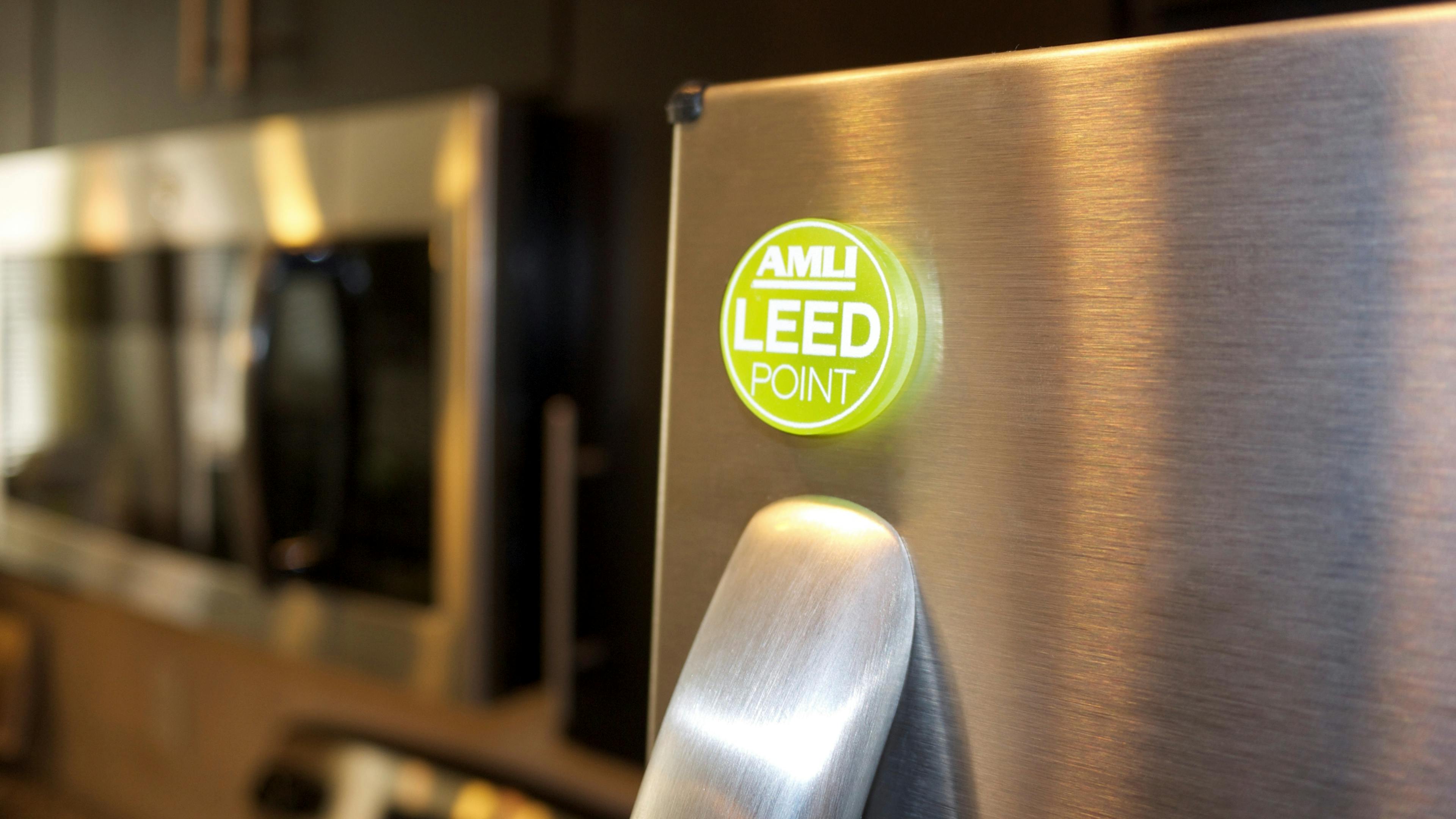 Closeup of green AMLI LEED coin above handle on an ENERGY STAR stainless steel refrigerator denoting sustainability