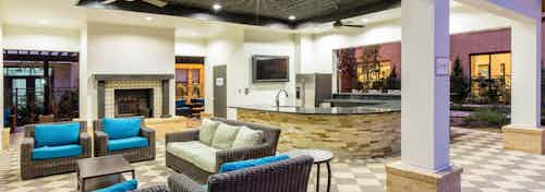Evening view of AMLI Campion Trail cabana with fireplace and comfortable seating and serving bar with large screen TV