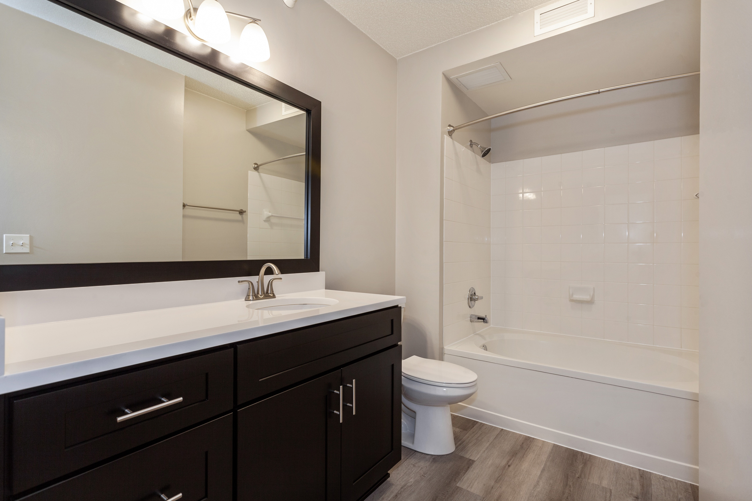 Interior of AMLI at Seven Bridges apartment bathroom with dark wood cabinets and white countertop and oval garden tub