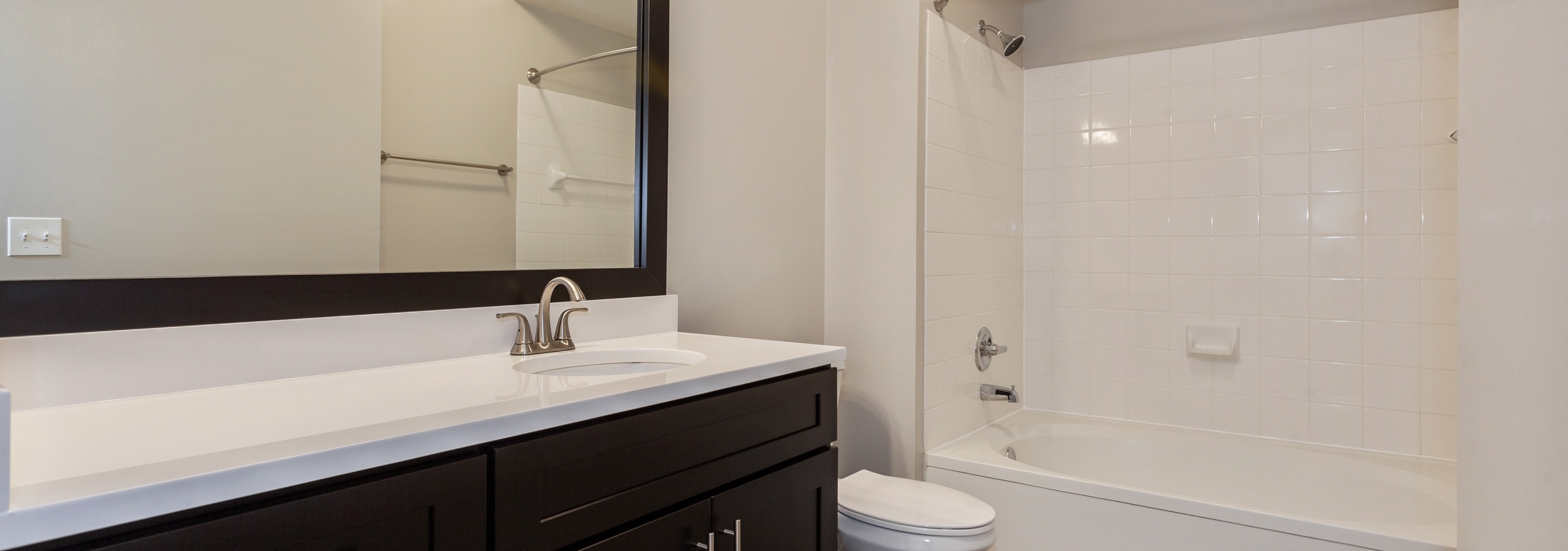 Interior of AMLI at Seven Bridges apartment bathroom with dark wood cabinets and white countertop and oval garden tub