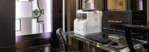 Interior of business center with computer station and printer and artwork in background at AMLI Uptown apartment building