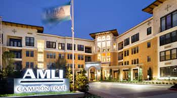 Exterior view of AMLI Campion Trail apartment building at night with a flag blowing in the wind on a clear evening