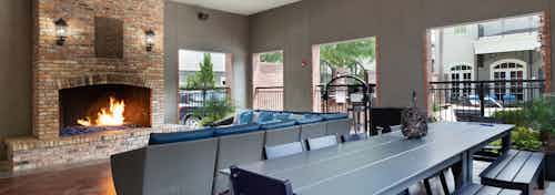 AMLI Memorial Heights cabana building with fireplace and couch seating and large table with bench and chairs in foreground
