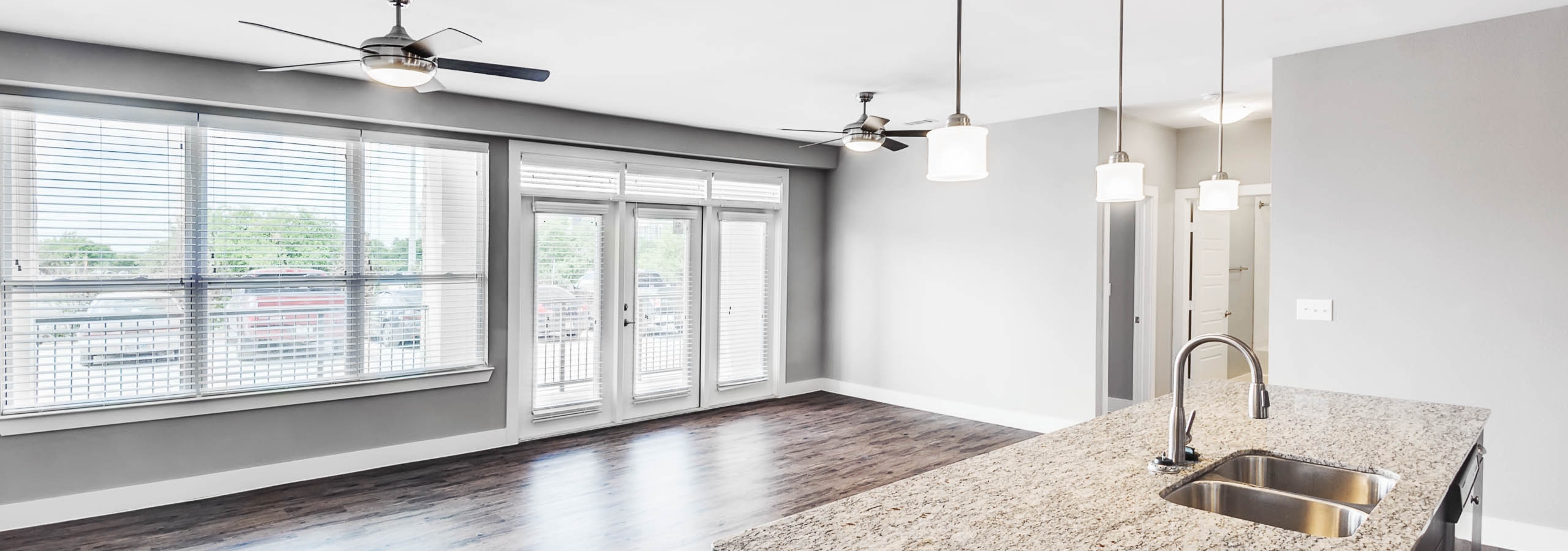 Interior view of AMLI at Escena apartment living and dining space with ceiling fans, large windows and door to patio