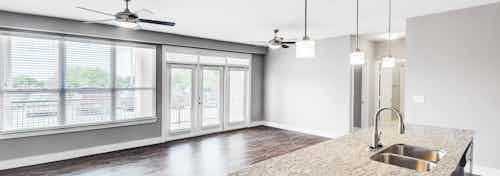 Interior view of AMLI at Escena apartment living and dining space with ceiling fans, large windows and door to patio