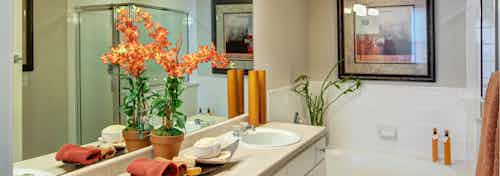 Interior of bathroom at AMLI Memorial Heights with double vanity with white cabinets and oval garden tub with tile surround