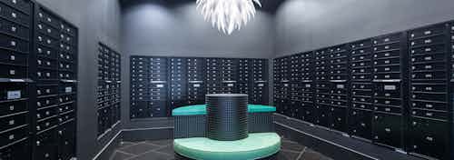 Mailroom at AMLI Uptown apartment building with three walls of mailboxes and green cushion and countertop in middle of room