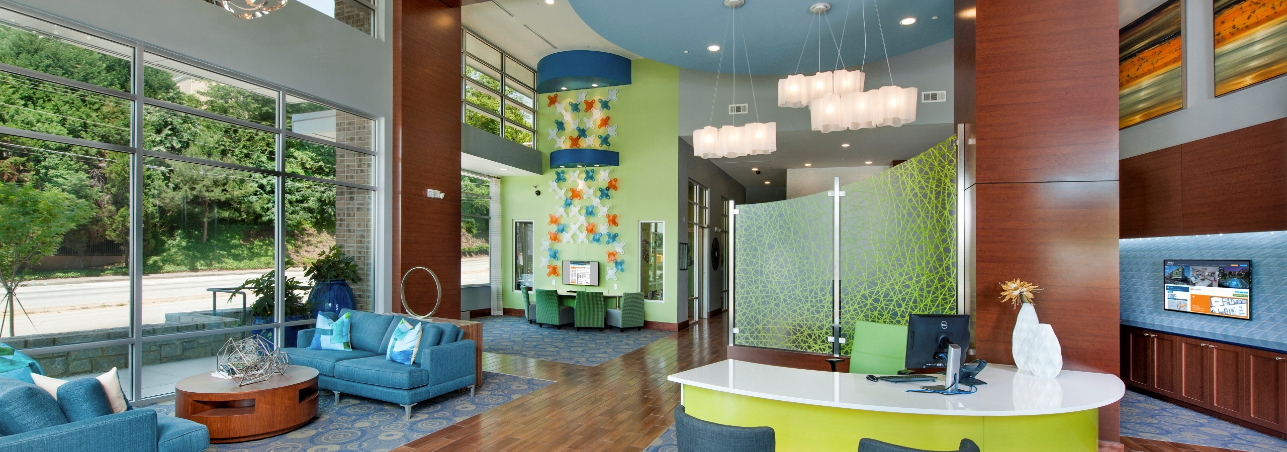 AMLI Piedmont Heights leasing office with a white desk with computers and blue couches with colorful decor and large windows