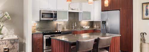 AMLI Design District apartment kitchen with Italian-inspired white and wood-grain cabinetry and granite countertops