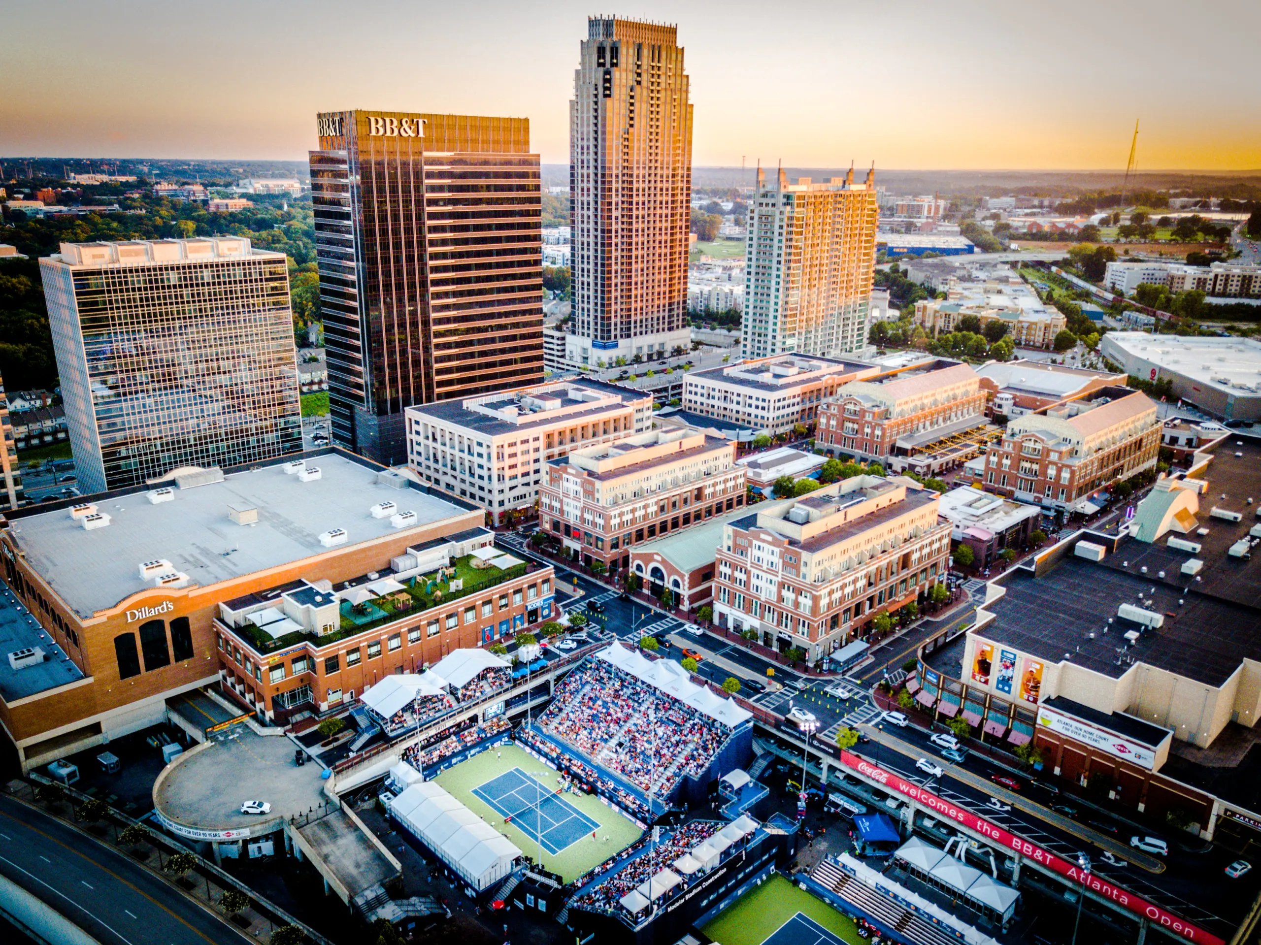 An aerial view of Atlantic Station at dusk with the skyscrapers and retail visible around the gridwork of streets below