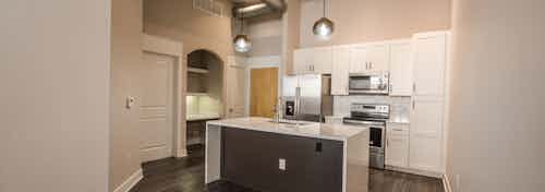 Interior view of AMLI Las Colinas apartment kitchen with stainless steel appliances and designer light fixtures