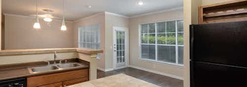 Interior view from island kitchen into living and dining rooms with large windows at AMLI Memorial Heights apartments