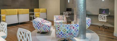 Interior of the business center at AMLI Sawgrass Village apartments with computers, a printer and colorful seating area
