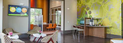 The leasing office at AMLI Sawgrass Village with high ceilings, seating and a coffee bar near an ornate wall mural