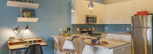 A small office area near the kitchen of an AMLI Sawgrass Village apartment with white cabinets and a breakfast bar