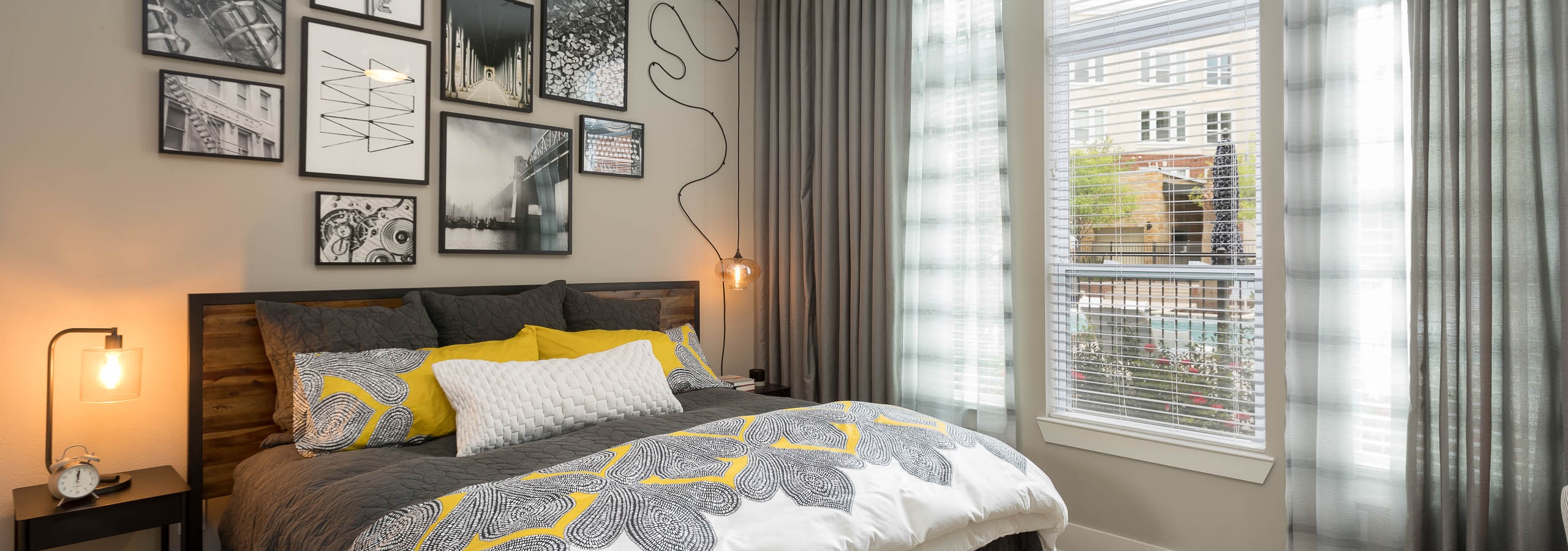 Interior view of AMLI Frisco Crossing apartment bedroom with bed and nightstands and large window with blinds and curtains