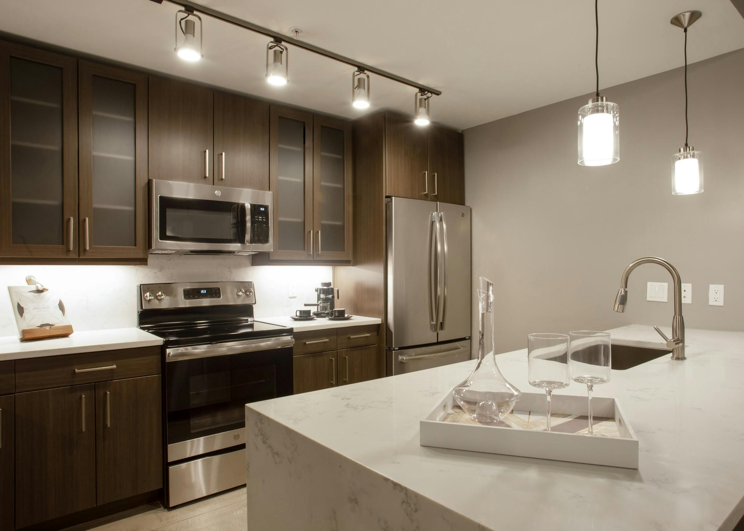 Close up of island in AMLI Downtown kitchen with modern light fixtures above and stainless steel appliances in background