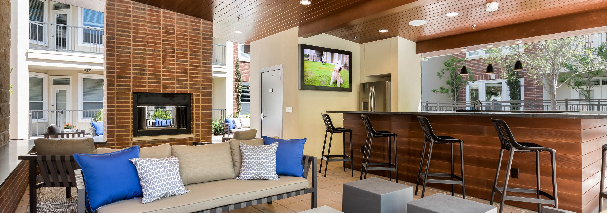 Daytime view of cabana at AMLI Frisco Crossing apartments with serving bar and big screen TV and seating and fireplace