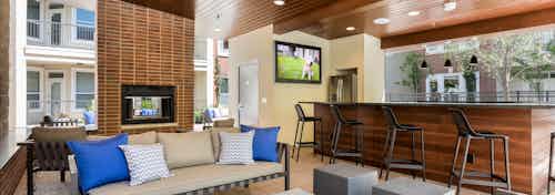 Daytime view of cabana at AMLI Frisco Crossing apartments with serving bar and big screen TV and seating and fireplace