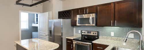 AMLI Memorial Heights apartment kitchen with dark wood cabinets, stainless steel appliances and granite island and counters